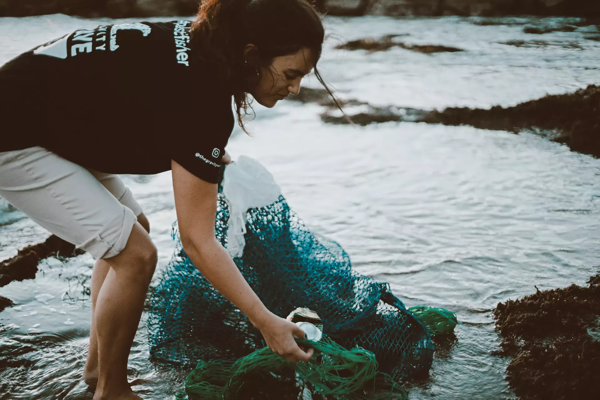 Imagen de una niña recogiendo plástico en el mar